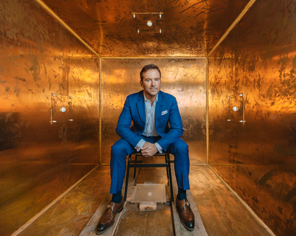 Dr Ben Johson sitting inside a copper box wearing a blue suit